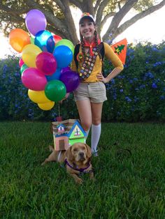 a woman standing in the grass with a dog and balloons