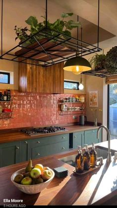 a kitchen with green cabinets and wooden counter tops, hanging plants over the stove top