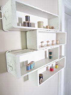 two white shelves with spools of thread on them