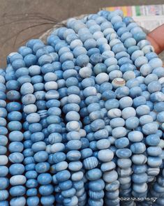 a bunch of blue beads sitting on top of each other in front of a person's hand