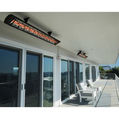 a balcony with chairs and lights on the side of it next to sliding glass doors