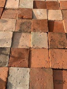 an orange and brown brick sidewalk with small white dots on it's edges, in the sun