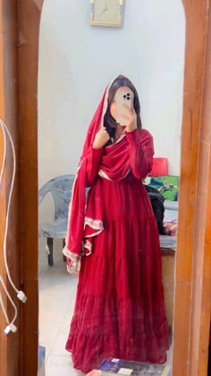 a woman in a red dress taking a selfie with her cell phone while wearing a mask