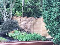 a wooden fence surrounded by plants and trees