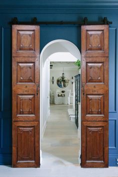 an open wooden door leading into a living room with blue walls and white flooring