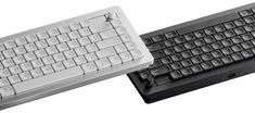 two keyboards sitting next to each other on a white surface