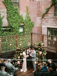 a couple getting married in front of an ivy covered balcony with candles and flowers on it