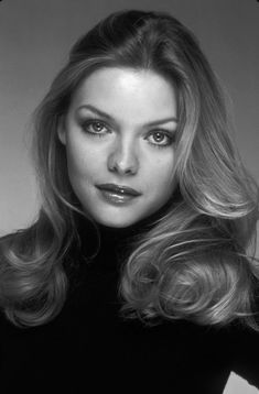 a black and white photo of a woman with long blonde hair wearing a turtle neck sweater