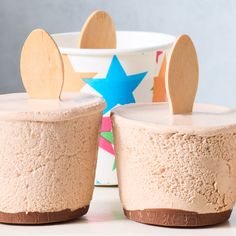 two dessert cups with wooden spoons sticking out of the top one cup has a star design on it