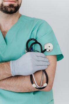 a man in scrubs and gloves holding a stethoscope on his arm