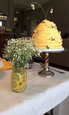 a table topped with a yellow cake covered in frosting and surrounded by small white flowers