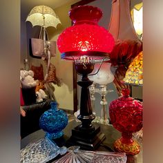 a table topped with lots of colorful glass vases next to lamps and other items