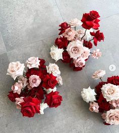 two vases filled with red and white flowers on the floor next to each other