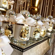 many perfume bottles are lined up on a table with white ribbons and bows around them