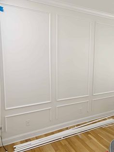 an empty room with white walls and wood flooring in the process of being painted