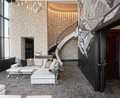 an elegant living room with white couches and chandelier hanging from the ceiling