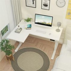 a white desk with a computer monitor and keyboard on it next to a bed in a room