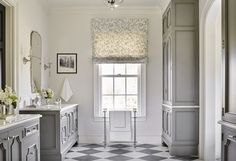 a bathroom with checkered tile flooring and white walls, along with gray cabinets