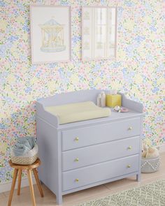 a baby's room with floral wallpaper and furniture