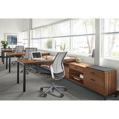 an office with several desks and chairs in front of large windows that have blinds on them