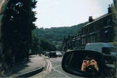 a rear view mirror on the side of a road with cars and buildings in the background