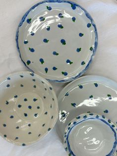 three white and blue bowls with dots on the rims are sitting on a tablecloth