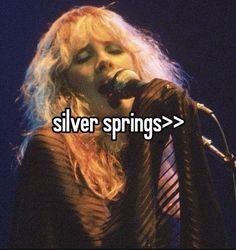 a woman singing into a microphone with the words silver springs in front of her face