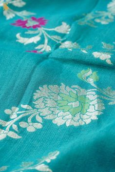 a close up view of a blue fabric with flowers on it and green, pink, yellow, and white colors