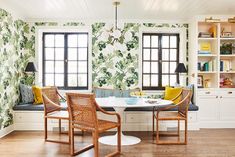 a dining room with green and white wallpaper, wicker chairs and a table