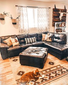 a dog laying on the floor in front of a sectional couch and ottoman with pillows