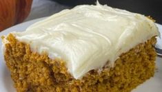 a close up of a piece of cake on a plate with a fork and pumpkin in the background