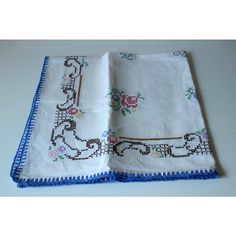 two white handkerchiefs with blue trim and flowers on the edges, one has a cross stitch border