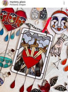 an assortment of stained glass and metal items are displayed on a white surface with red ribbon