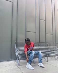 a man sitting on a metal bench in front of a building with his head down