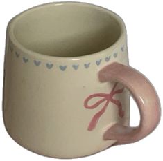 a pink and white coffee cup with a bow on the handle is sitting in front of a white background