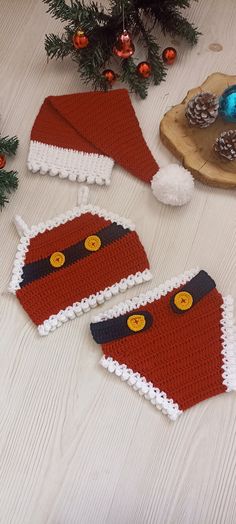 two knitted christmas stockings sitting on top of a wooden table next to pine cones