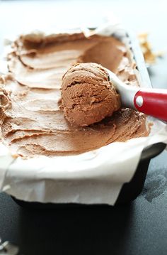 a scoop of chocolate ice cream is being scooped from a bowl with a red spatula