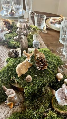 the table is covered with moss and little deer figurines, pine cones, and candlesticks