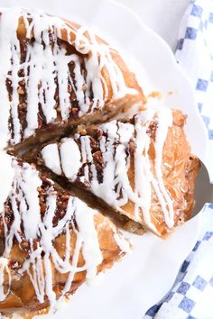 a white plate topped with a pastry covered in icing on top of a checkered table cloth