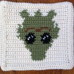 a crocheted dishcloth with an image of a green creature on the front