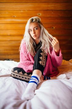 a woman with blonde hair sitting on a bed