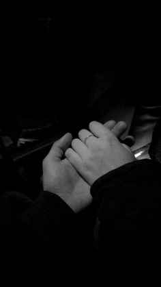 two people holding hands in the dark with their arms folded over each other's shoulders