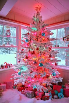 a brightly lit christmas tree in front of a window