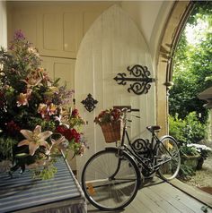 a bicycle parked in front of a white door with flowers on the outside and inside