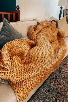 a person laying on a couch covered in a blanket