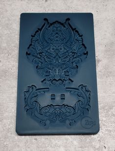 a cookie sheet with an ornate design on the front and back of it, sitting on top of a cement surface