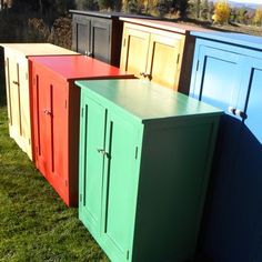 several different colored cupboards sitting in the grass