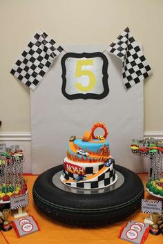 a birthday cake is on top of a tire at the end of a race track