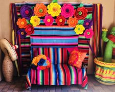 a colorful bench with flowers on it next to potted cacti and cactus