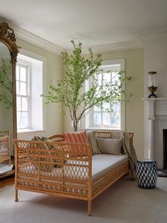 a living room with a couch, mirror and potted tree in the corner next to it